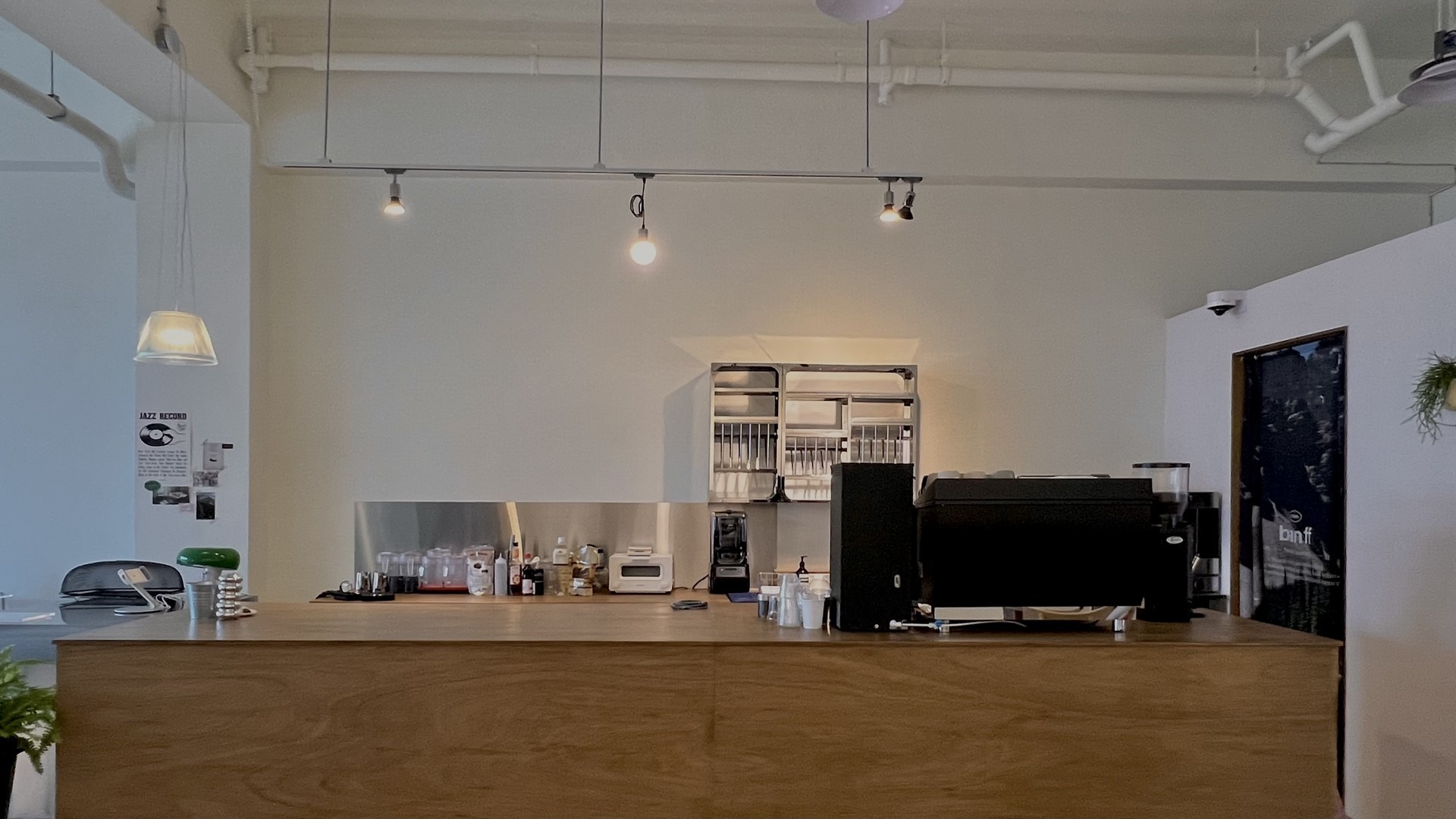 tes design(테스 디자인)이 연출한 카페 헵의 메인 바 카운터 정면 모습으로 미니멀한 구성과 은은한 전구색 조명이 편안한 느낌을 주는 공간